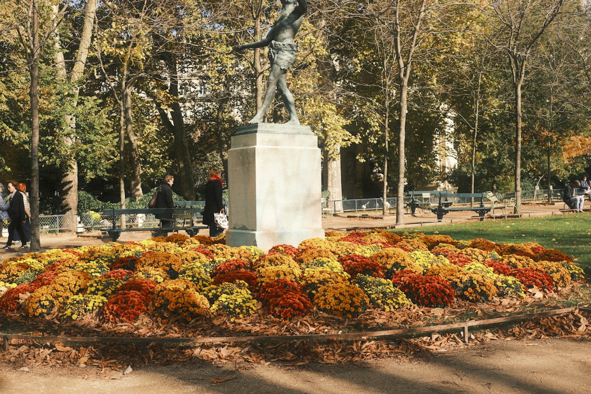 Statue in a park surrounded by colorful autumn flowers related to Enhancing Your Bedroom with a Stylish Bench