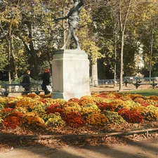 Statue in a park surrounded by colorful autumn flowers related to Enhancing Your Bedroom with a Stylish Bench