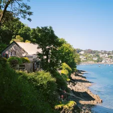 Stone cottage on a sunny hillside beside a blue bay. related to Unveiling the Charm of Harbor House Bedding: Style and Comfort