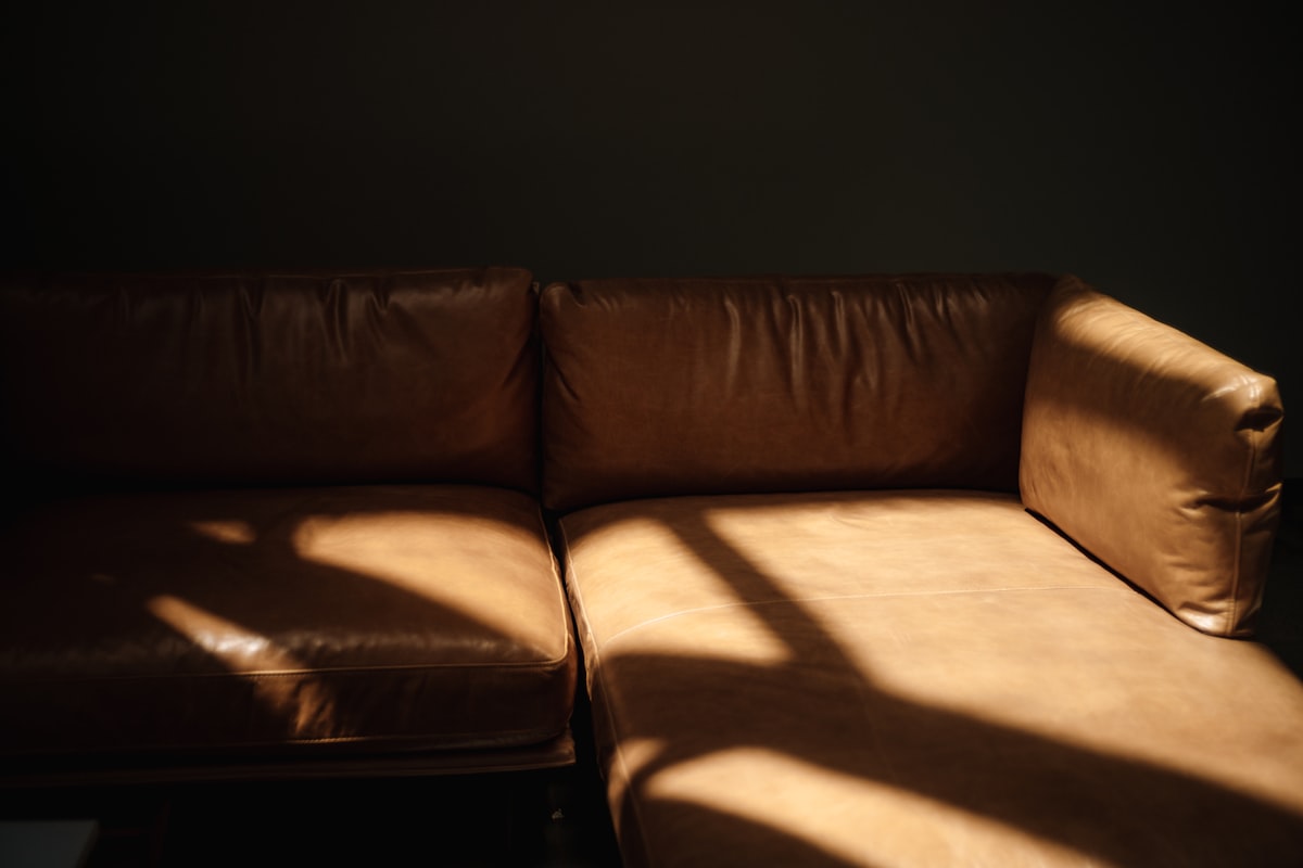 Sunlight casts dramatic shadows on a brown leather sofa. related to Leather Sofa Beds: Ultimate Comfort and Style