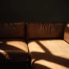 Sunlight casts dramatic shadows on a brown leather sofa. related to Leather Sofa Beds: Ultimate Comfort and Style