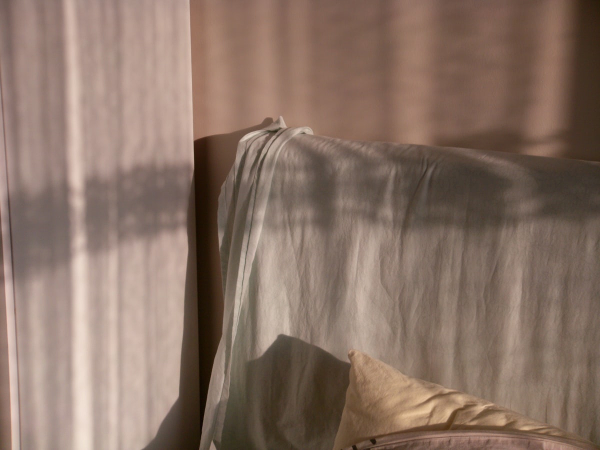 Sunlight casts shadows on a draped sofa. related to Timeless Elegance: The Bed Skirt Queen