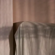 Sunlight casts shadows on a draped surface. related to Weaving Whimsy: A Guide to Magical Thinking Bedding