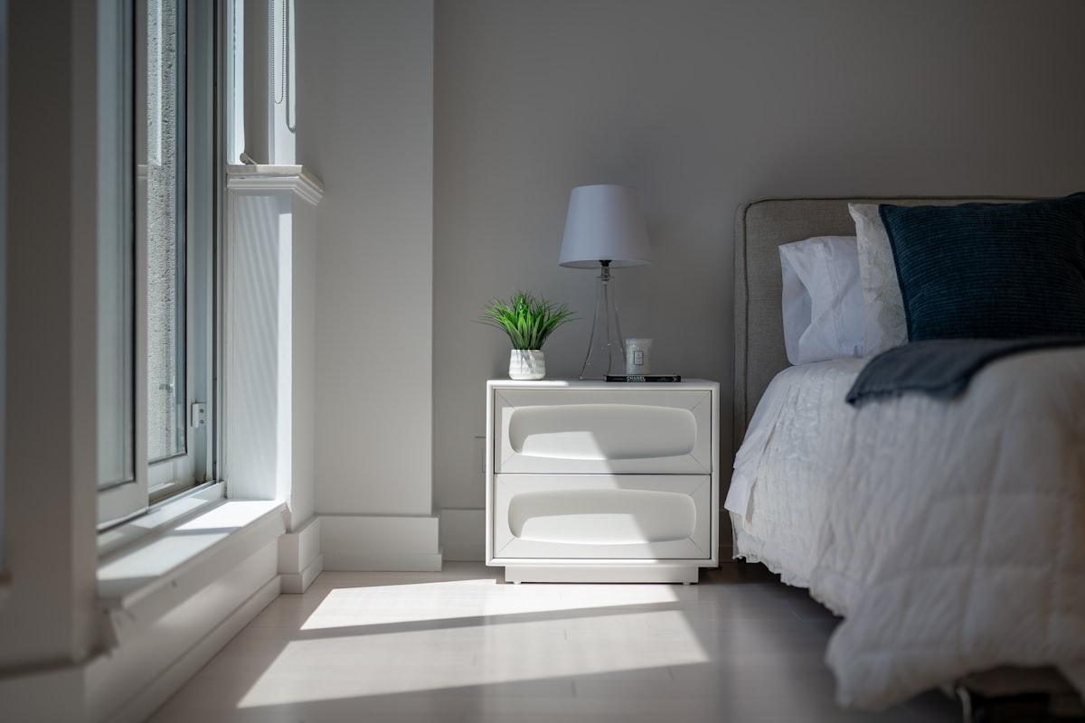 Sunlight illuminates a cozy bedroom with a bed and nightstand. related to Elevate Your Sleep Experience with Luxury Bed Sheets