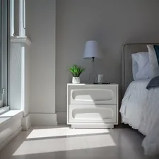 Sunlight illuminates a cozy bedroom with a bed and nightstand. related to Elevate Your Sleep Experience with Luxury Bed Sheets