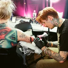 Tattoo artist working on a client's arm related to Chris Madden Valance: The Talented Singer-Songwriter