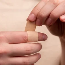 The man seals the wound with adhesive plaster. The medicine. Injury. Wound. Infection. First aid. Pain related to Coverlet Adhesive Bandages: A Guide to Effective Wound Care