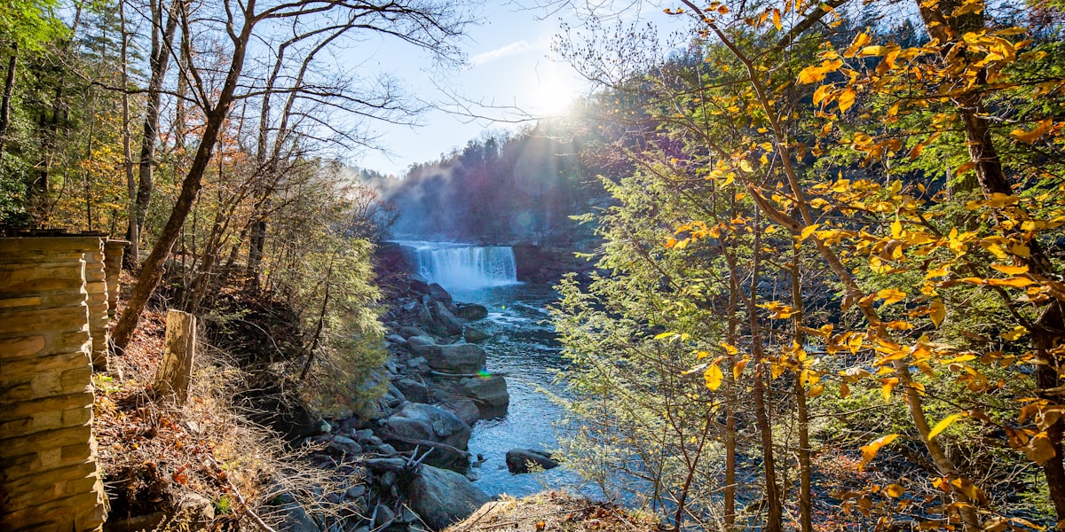 the sun is shining over a waterfall in the woods related to Experience Serenity at Cumberland Falls Bed and Breakfast Inn