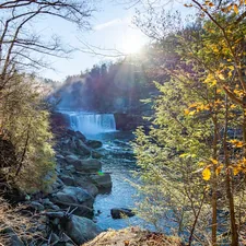 the sun is shining over a waterfall in the woods related to Experience Serenity at Cumberland Falls Bed and Breakfast Inn