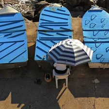 Three blue surfboards with a person under an umbrella related to Tanning in the Past: The Lowdown on Used Tanning Beds