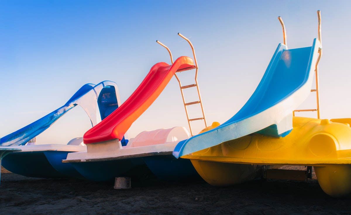 Three colorful pedal boats with slides under a clear sky. related to Unleashing Slumber Fun for Kids: The World of Beds with Slides