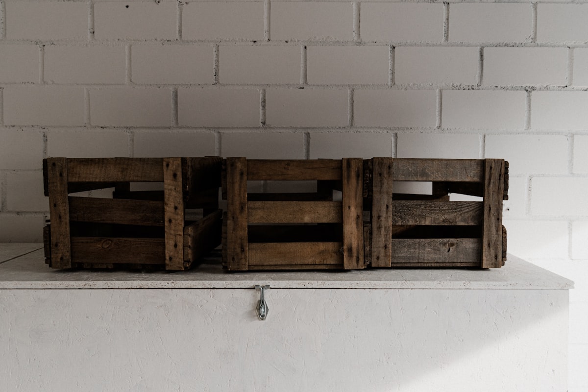Three empty wooden wine boxes in front of a white wall. related to Elevate Your Sleep: The Benefits of a Wooden Crate Bed Frame