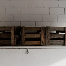 Three empty wooden wine boxes in front of a white wall. related to Elevate Your Sleep: The Benefits of a Wooden Crate Bed Frame