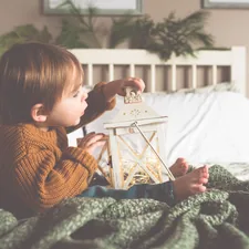 toddler holding candle lantern while sitting on bed related to Best Toddler Beds for Boys: Top Picks and Ultimate Guides