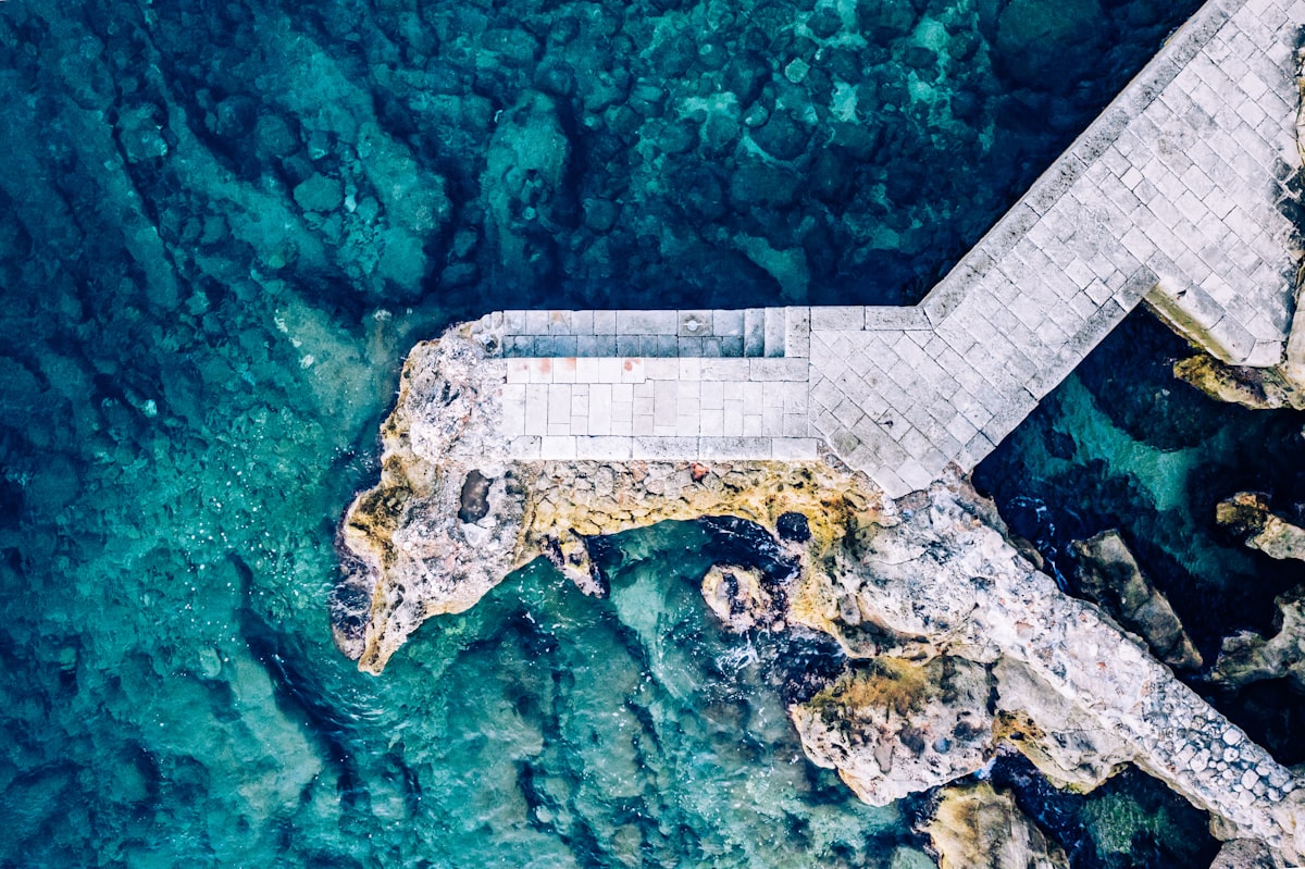 Top-down view rocky beach and clear blue water background.Beach located on the Adriatic sea coastline, Dubrovnik. Breakwater aerial drone view along the city coast. related to The Ultimate Guide to Platform Bed Foundation