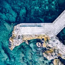 Top-down view rocky beach and clear blue water background.Beach located on the Adriatic sea coastline, Dubrovnik. Breakwater aerial drone view along the city coast. related to The Ultimate Guide to Platform Bed Foundation