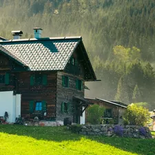 Traditional wooden house on a green hillside with mountains. related to The Timeless Charm of Wooden Day Beds: A Perfect Blend of Comfort and Style