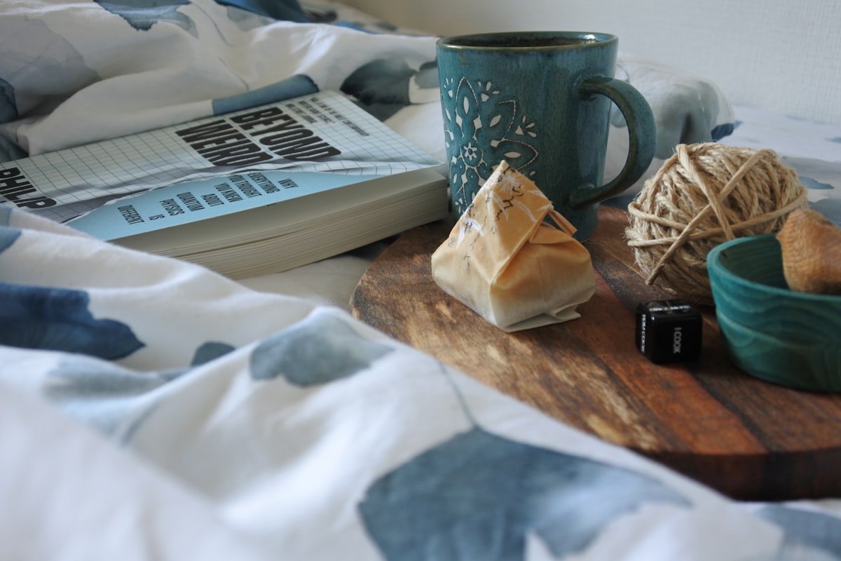 Turkish coffee on a wooden tray and a book on the bed.  related to Weaving Whimsy: A Guide to Magical Thinking Bedding