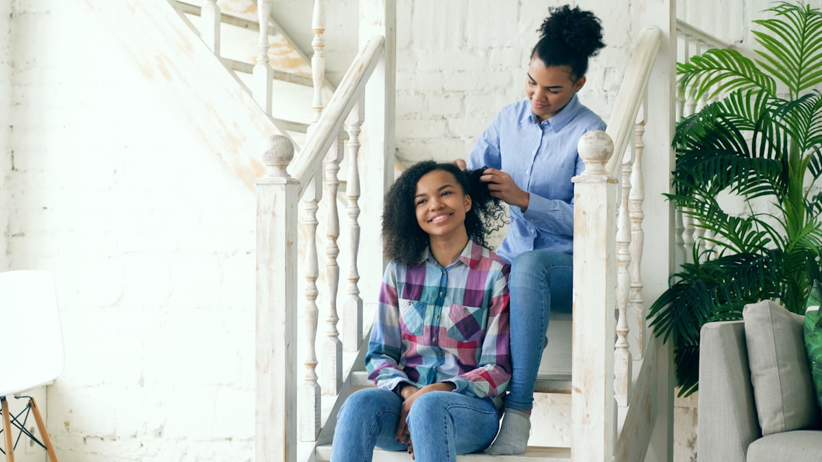 Two african american curly girls sistres make fun curly hairstyle each other and have fun related to Enhancing Comfort and Safety at Home