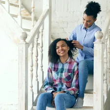 Two african american curly girls sistres make fun curly hairstyle each other and have fun related to Enhancing Comfort and Safety at Home
