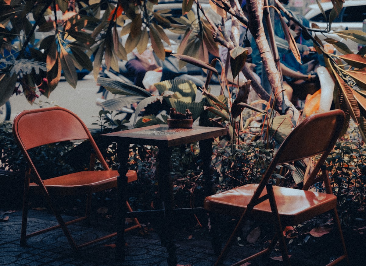 Two chairs and a table under leafy trees related to Enhance Your Outdoor Space with the Best Clay Chimineas at Lowes