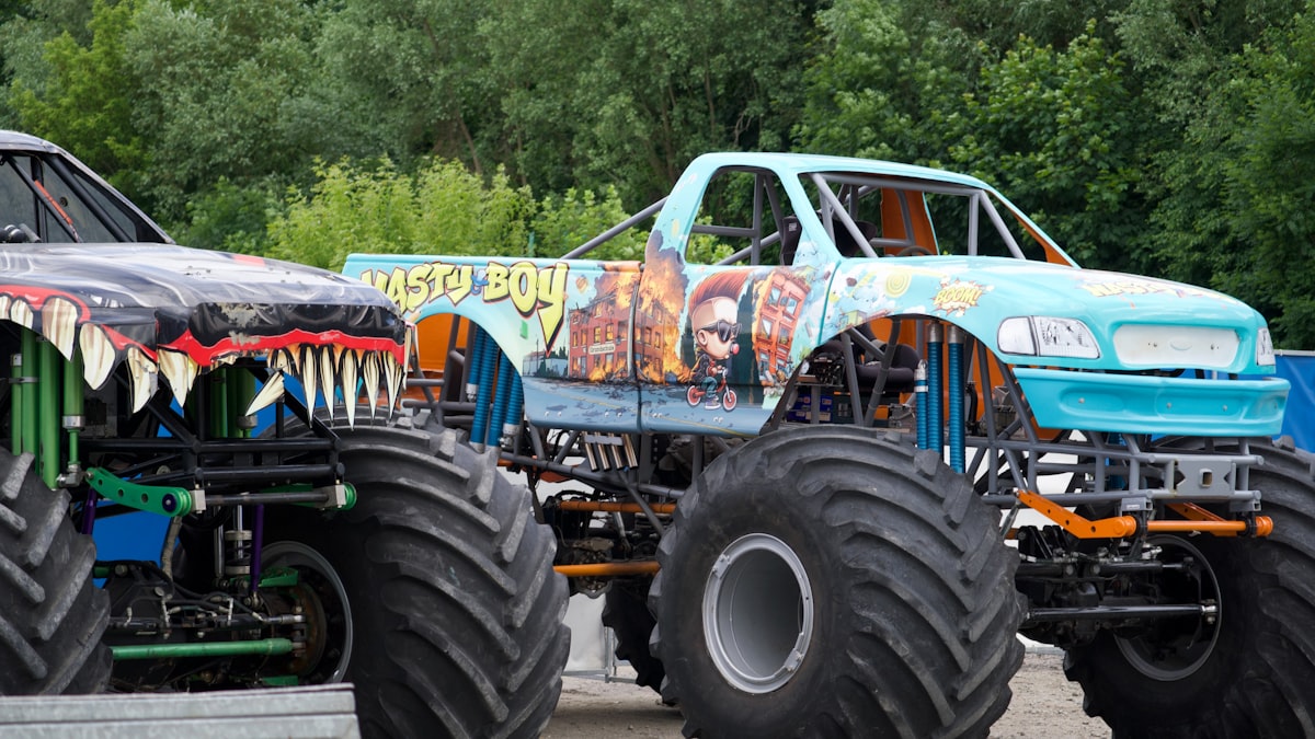 Two monster trucks with large tires parked outdoors. related to Monster Truck Bedding: The Ultimate Decaf Crash Shelter