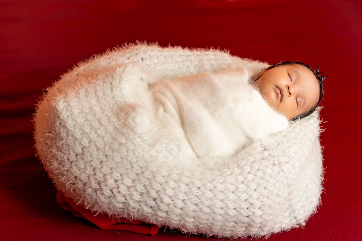 Two months old baby sleeping wrapped in white clothes. related to The Ultimate Guide to Choosing the Perfect Baby Bean Bag Bed
