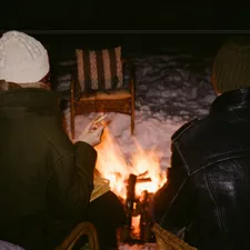 Two people sit by a campfire at night. related to Camping Beds for a Cozy Night Under the Stars: Walmart Options