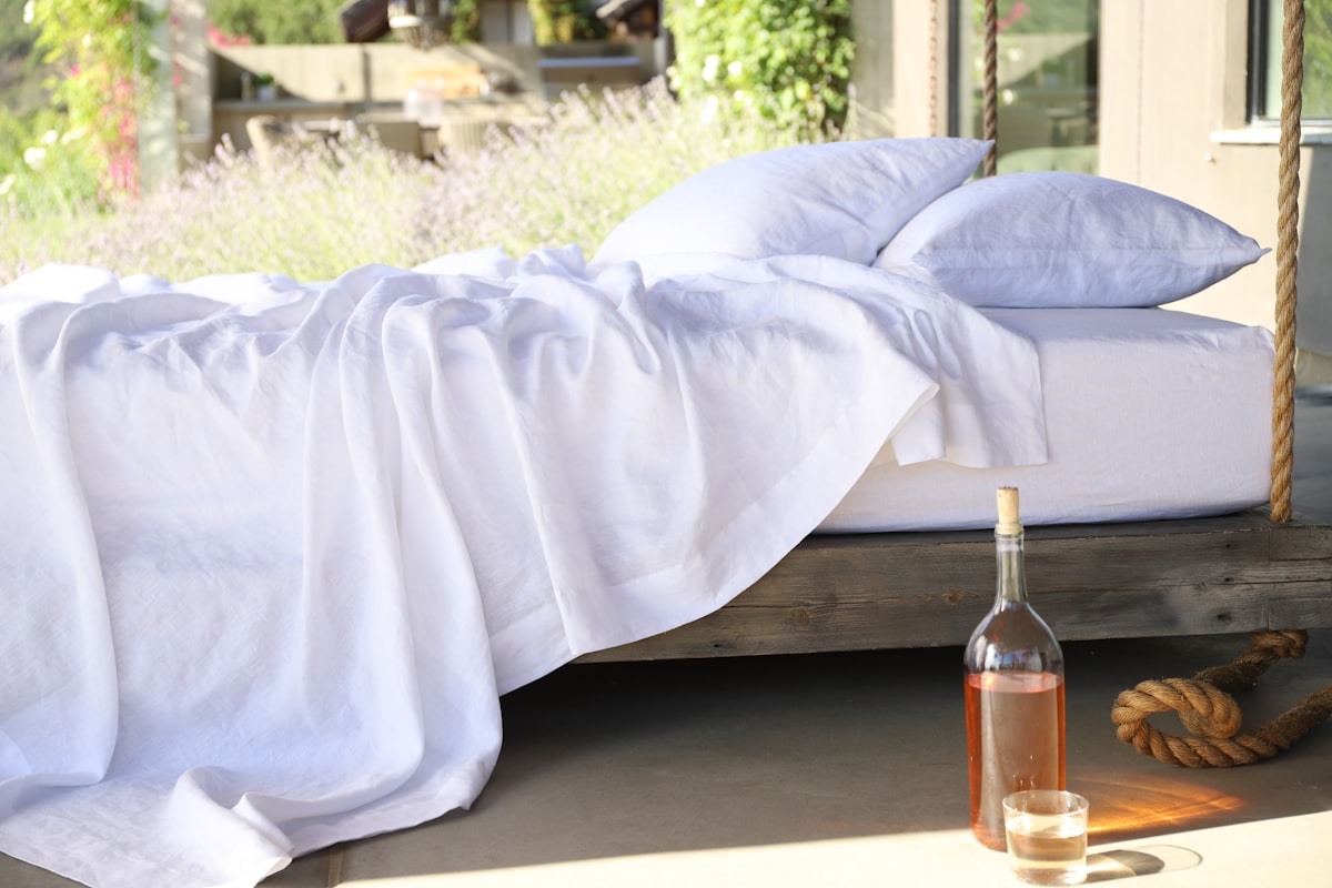 two white pillows on bed and glass of bottle near drinking glass on floor related to Twin Coverlet Set
