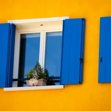 two windows with blue shutters and a potted plant related to Solid Color Valances for Windows