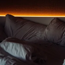 Unmade bed with warm ambient lighting above related to The Enchanting World of Lights Around Bed