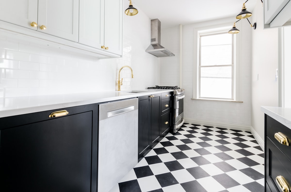 White & Black kitchen with gold faucets and gold finishings. Black & white checkered floor. Marble countertop. Black kitchen cabinets. White kitchen cabinets.  related to Exploring the Beauty of Patterns for Kitchen Valances