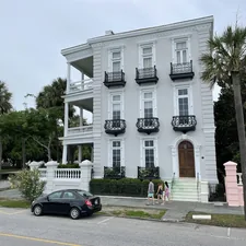 white concrete building with black sedan parked in front related to Historic Southern Charm: Bed and Breakfast in Charleston SC