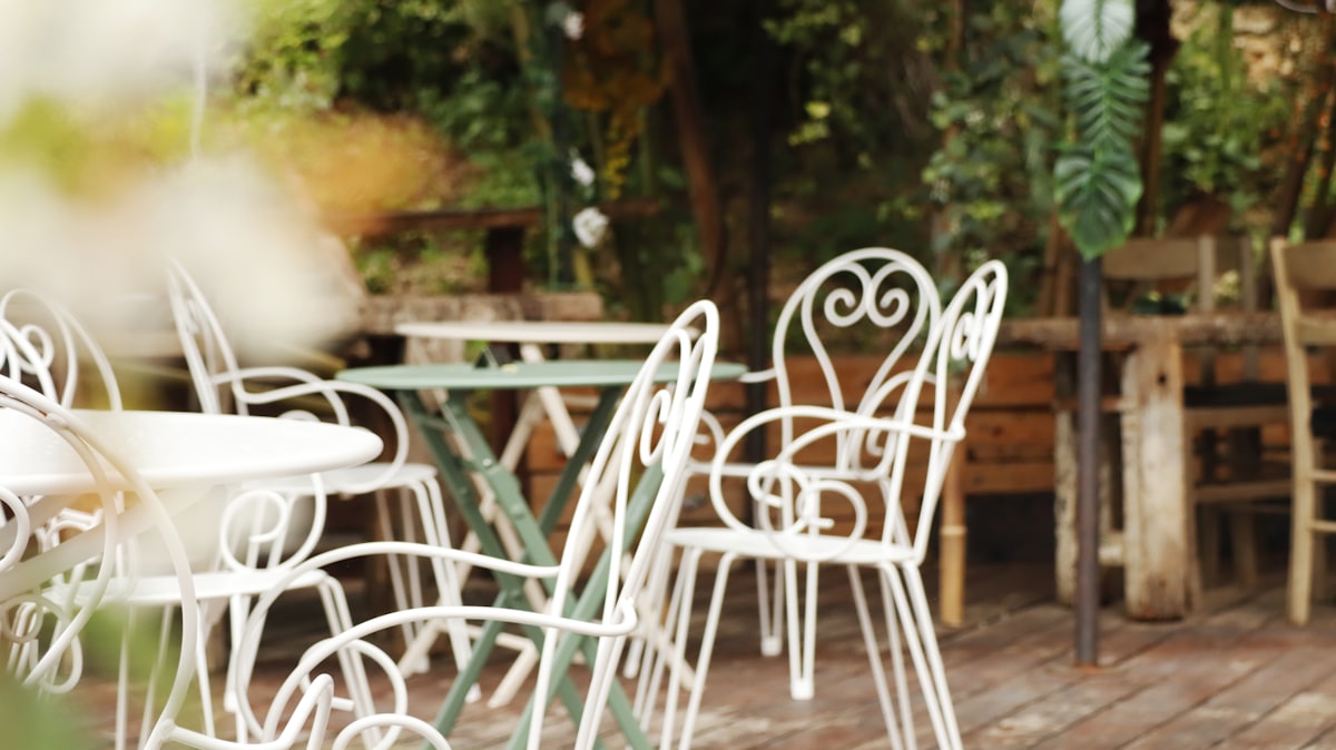 White metal chairs and tables on a wooden deck. related to Transform Your Patio with an Outdoor Bed