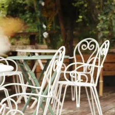 White metal chairs and tables on a wooden deck. related to Transform Your Patio with an Outdoor Bed
