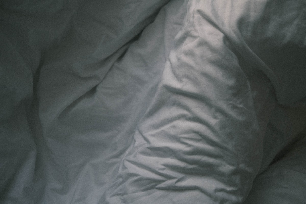 white textile on black textile related to Coverlet vs Duvet: What's the Difference?