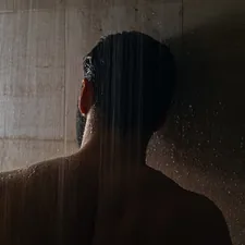 woman in black hair in front of white curtain related to The Ultimate Guide to Shower Caddies