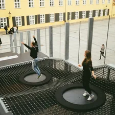 woman in black jacket and black pants standing on round black metal table related to Innovative Sleep Solutions with Trampoline Beds