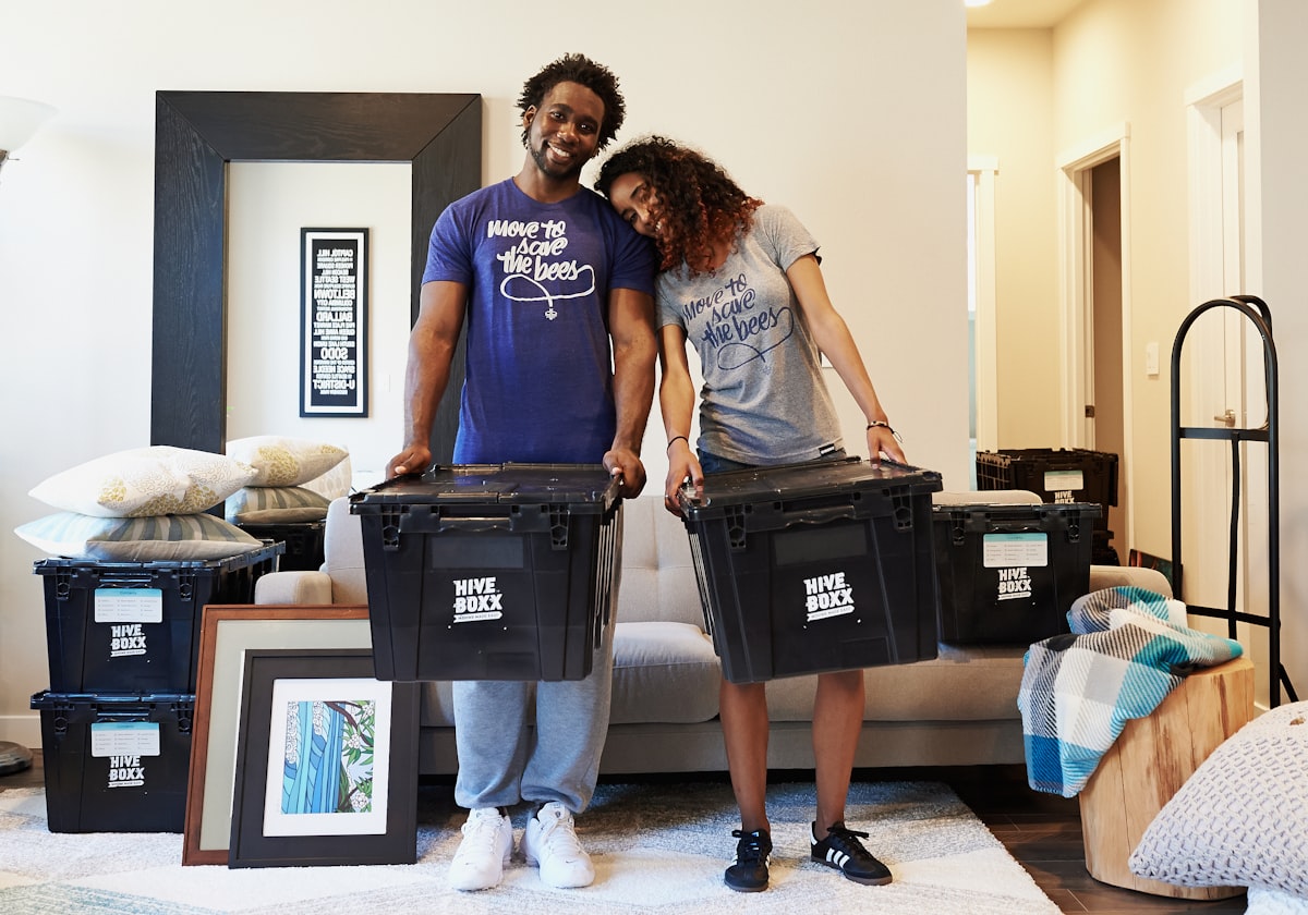 woman in blue tank top and gray leggings holding black suitcase related to Cozy Up with Style: Top Trends in Crate and Barrel Bedding