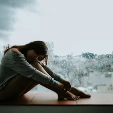 woman in gray long sleeve shirt sitting on window related to When Depression Keeps You in Bed: Understanding and Overcoming the Struggle