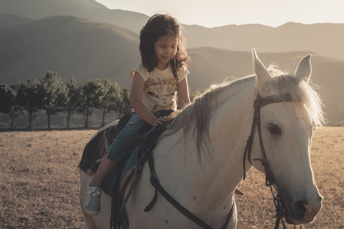 woman in white shirt riding white horse during daytime related to The Ultimate Guide to Stylish Horse Bedding for Equestrian Girls