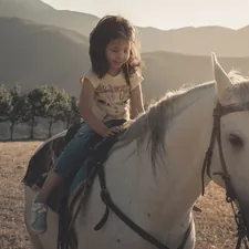 woman in white shirt riding white horse during daytime related to The Ultimate Guide to Stylish Horse Bedding for Equestrian Girls