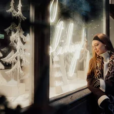 Woman looking at a festive shop window display related to Window Wonderland: Discover the Magic of Free Valance Patterns