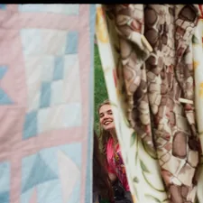 Woman peeking through colorful patterned curtains related to Cozy Comfort: Coverlets & Quilts