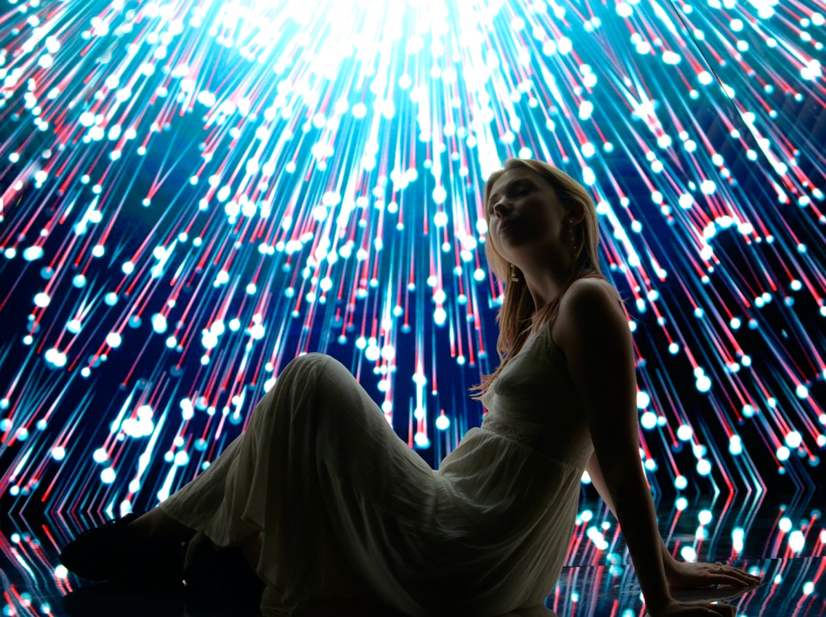 Woman poses with a colorful, bright, light display. related to Enchant Your Space with a Supernatural Bed Set