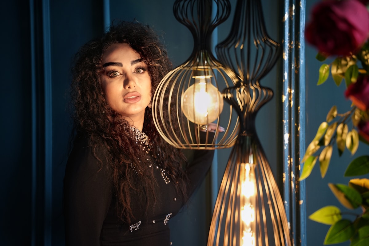 Woman posing with decorative lamps and flowers related to Elegant Decor: The Beauty of Black Lace Valance