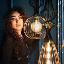 Woman posing with decorative lamps and flowers related to Elegant Decor: The Beauty of Black Lace Valance