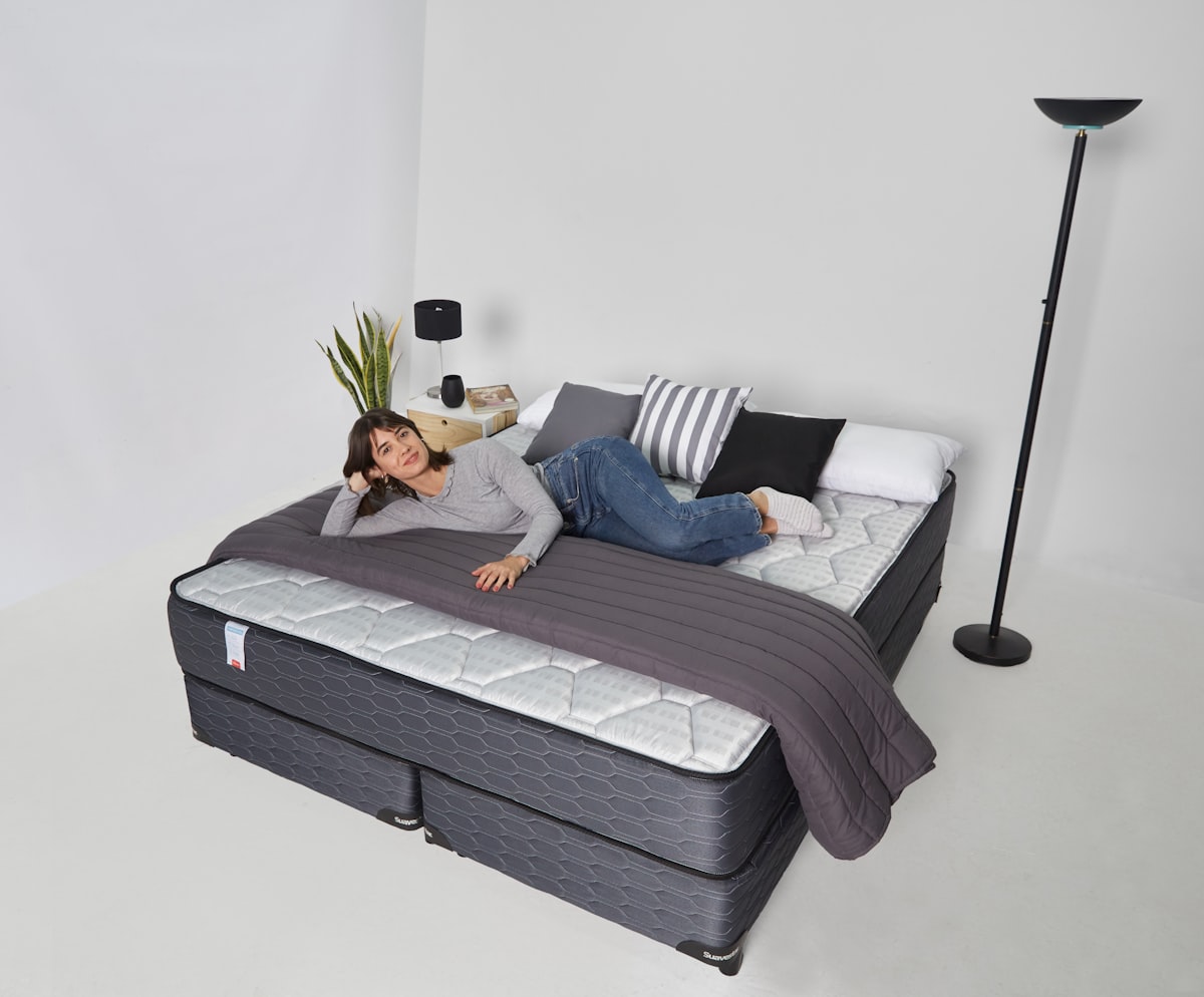 Woman relaxing on a large bed with pillows related to Coverlets for Daybeds: Enhancing Comfort and Style