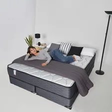 Woman relaxing on a large bed with pillows related to Coverlets for Daybeds: Enhancing Comfort and Style