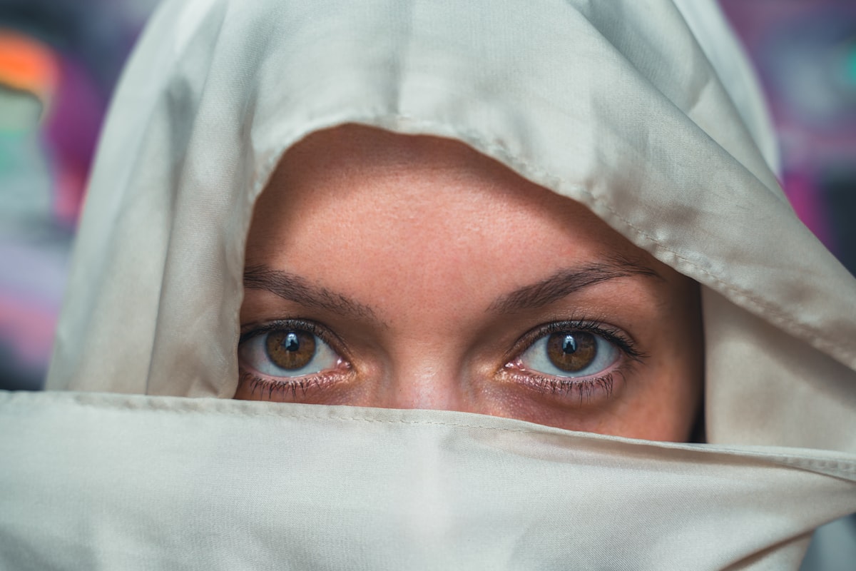 Woman's eyes peek through white fabric with graffiti background related to White Eyelet Valances